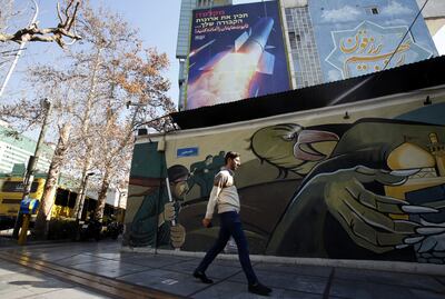 A man walks past a billboard depicting Iranian missiles with a message in Persian and Hebrew reading 'prepare your coffins', on a building in Palestine Square, Tehran on Tuesday. EPA