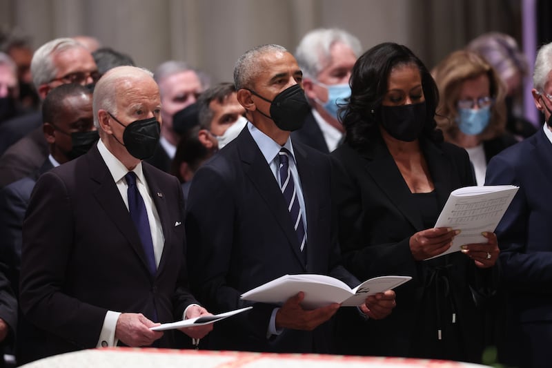 US President Joe Biden, former US president Barack Obama and former first lady Michelle Obama hold hymn sheets. AFP
