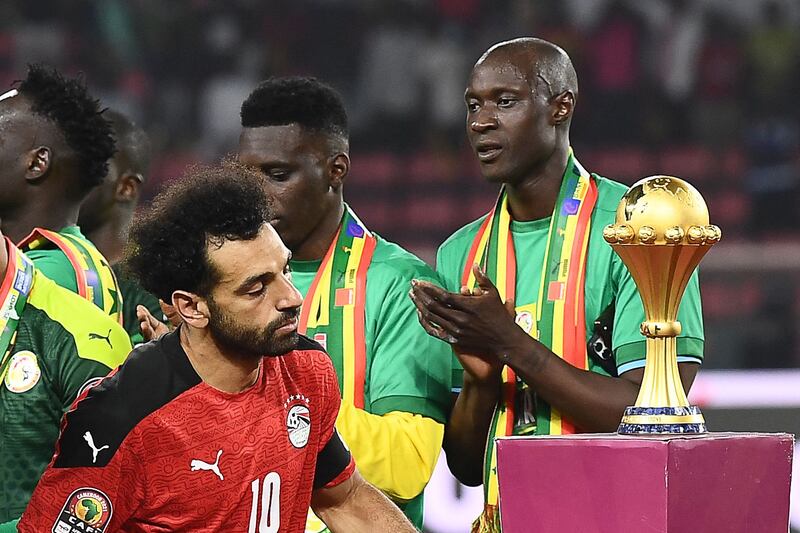 Mohamed Salah walks past Africa Cup of Nations trophy. AFP