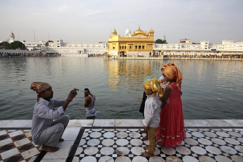 A visitor takes pictures of children at the Golden Temple, the holiest of Sikh shrines on the occasion of the Visakhi festival in Amritsar, India. Raminder Pal Singh / EPA