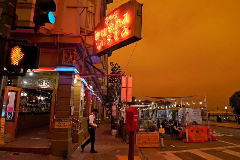 Under darkened skies from wildfire smoke, a waiter carries a tray of Irish Coffee to people having lunch at the Buena Vista Cafe, in San Francisco. AP Photo