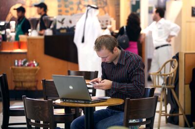 DUBAI, UNITED ARAB EMIRATES - June 28:   A man using his laptop computer and mobile phone at the Starbucks cafe in the Ibn Battuta Mall in Dubai on June 28, 2008.  (Randi Sokoloff / The National)