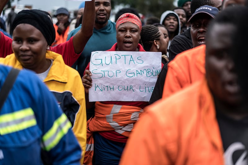 A demonstrator holds a placard that reads 'Guptas - stop gambling with our lives' outside the mine. AFP