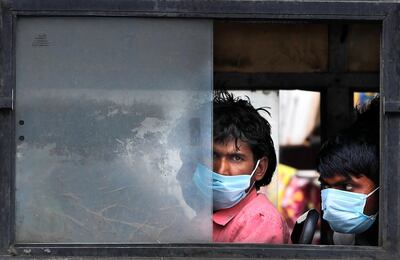 Migrant laborers sit in a bus to travel to their villages following a six-day lockdown put into place to control the rising cases of coronavirus infections, in New Delhi, India, Tuesday, April 20, 2021. India recorded over 250,000 new infections and over 1,700 deaths in the past 24 hours alone, and the U.K. announced a travel ban on most visitors from the country this week. (AP Photo/Manish Swarup)