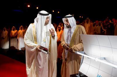 MADINAT ZAYED, WESTERN REGION OF ABU DHABI, UNITED ARAB EMIRATES - March 17, 2013: HE Dr Sultan Ahmed Al Jaber CEO of Masdar (L), speaks with HH Sheikh Khalifa bin Zayed Al Nahyan President of the UAE and Ruler of Abu Dhabi (C), about the Parabolic Through (seen right) during the Shams 1 Concentrated Solar Power plant opening ceremony. Shams 1 is a project of the Shams Power Company, a subsidiary of Masdar, in association with Total and Abengoa Solar..( Ryan Carter / Crown Prince Court - Abu Dhabi ).---