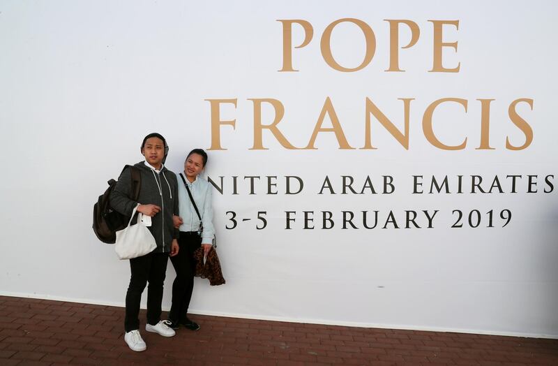 People pose for a photo in front of a sign welcoming Pope Francis in Abu Dhabi. Reuters