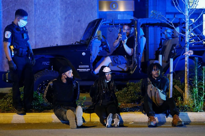 A passerby in a vehicle takes a photo of three protesters being detained during a third night of unrest in Richmond, Virginia. AP Photo