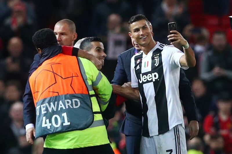 Juventus' Cristiano Ronaldo takes a selfie as stewards apprehend a pitch invader. Reuters