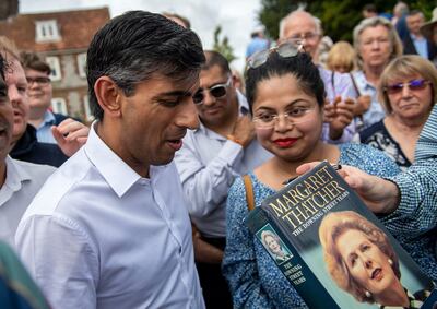 Rishi Sunak is handed a copy of former UK prime minister Margaret Thatcher's book to sign at a campaigning event on Saturday. AP