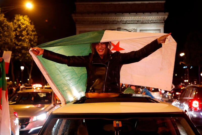 Algeria supporters with the country's national flag celebrate after Algeria won the 2019 Africa Cup of Nations (CAN) semi-final football match against Nigeria, on the Champs-Elysee avenue in Paris on July 14, 2019. Riyad Mahrez rifled in a stoppage-time free-kick to earn Algeria a dramatic 2-1 victory over three-time champions Nigeria on July 14 and set up a rematch with Senegal in the Africa Cup of Nations final. / AFP / Zakaria ABDELKAFI
