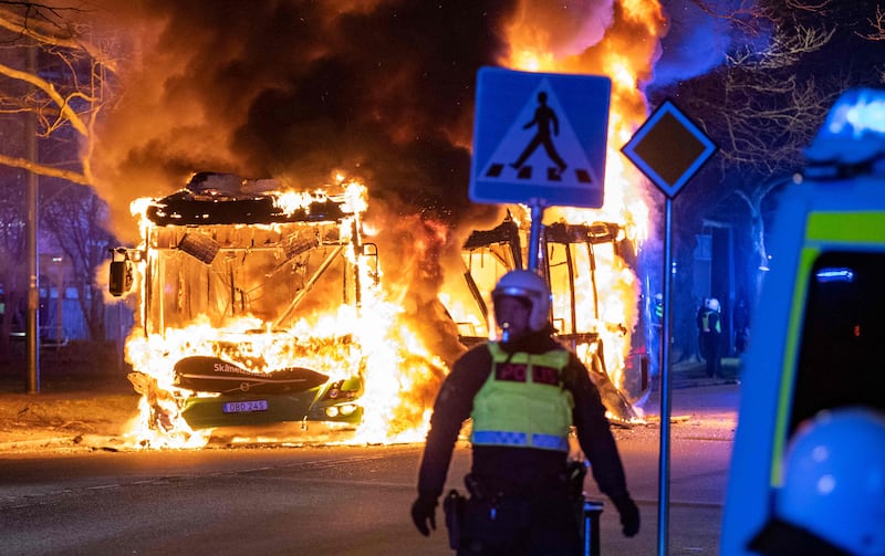 A police officer stands in front of a blazing bus, in southern Swedish city Malmo. AFP