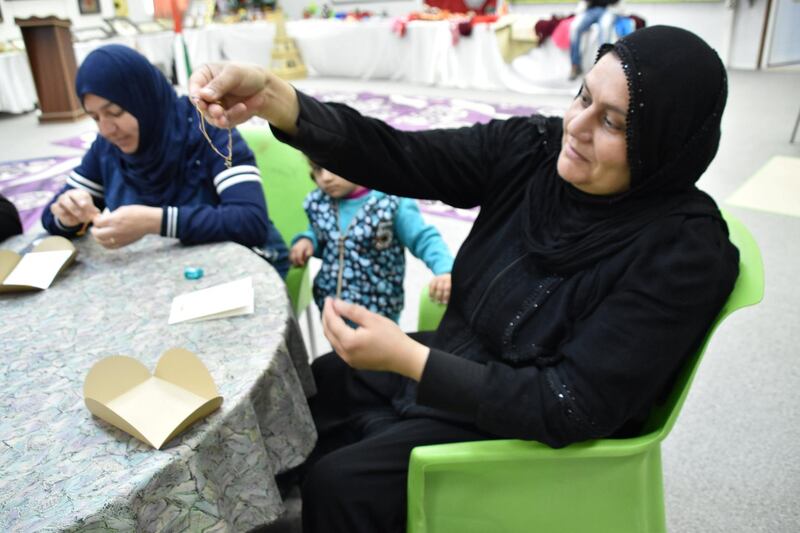 A woman examines her handiwork on the charity charm bracelets created by the camp's members for MKS Jewellery 