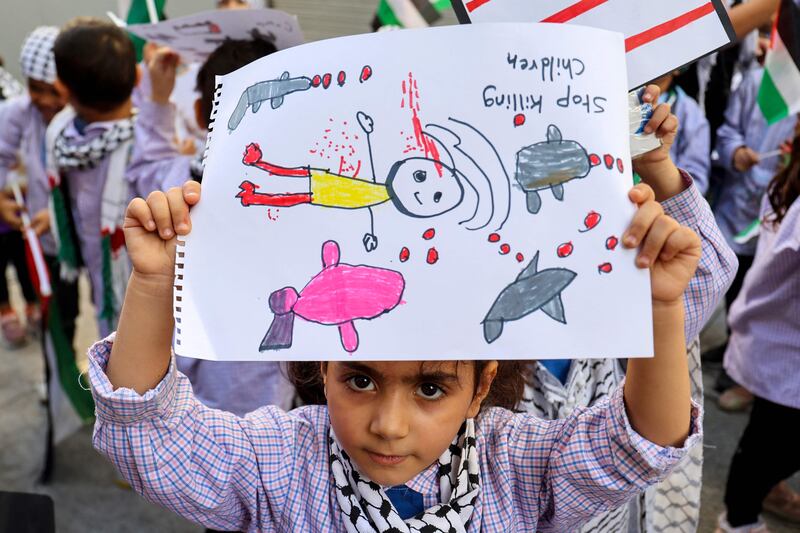 A Palestinian girl holds up a drawing as children join a protest on Tuesday at refugee camps near Beirut against the Gaza war. It is an indictment of the adult world that children must show such resilience. AFP
