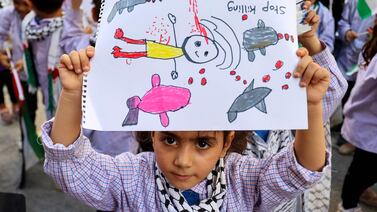 A Palestinian child holds up a drawing as refugee children living in Lebanese camps take part in a protest outside the International Red Cross building in Beirut denouncing the killing of children in Gaza. AFP