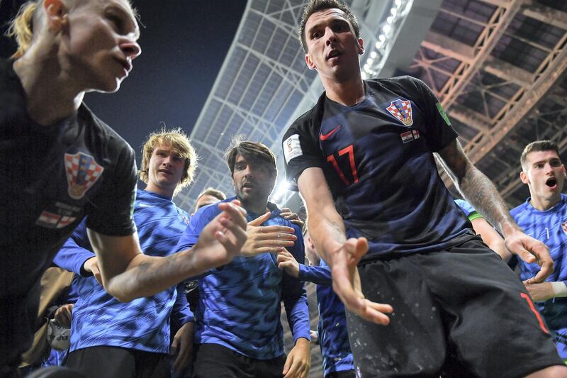 Croatia's forward Mario Mandzukic (C) offers to help AFP photographer Yuri Cortez after he fell on him with teammates while celebrating their second goal during the Russia 2018 World Cup semi-final football match between Croatia and England at the Luzhniki Stadium in Moscow on July 11, 2018. / AFP PHOTO / Yuri CORTEZ / RESTRICTED TO EDITORIAL USE - NO MOBILE PUSH ALERTS/DOWNLOADS
