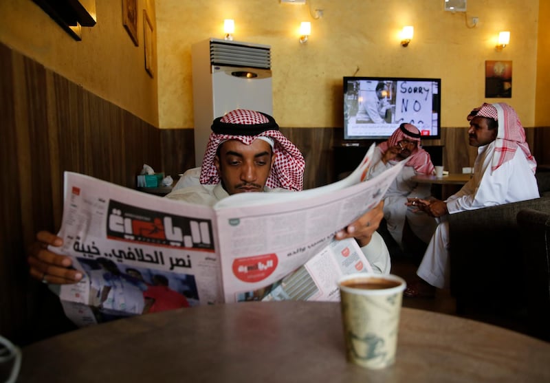 A man reads Al-Riyadiah sports newspaper as others watch oil news at a coffee shop in Jeddah, Saudi Arabia.AP Photo