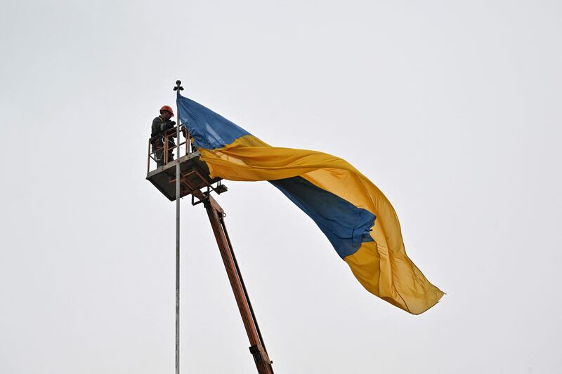 Workers put an Ukrainian flag on a pole in the centre of Makariv. AFP