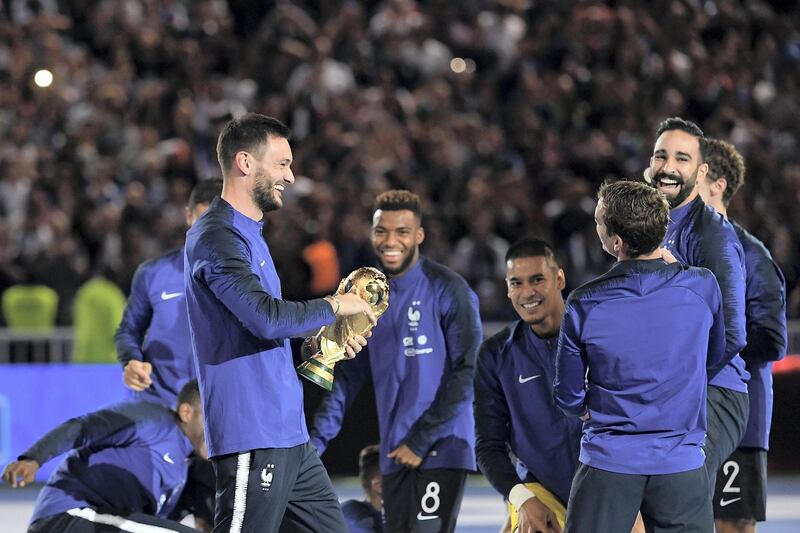 France's goalkeeper Hugo Lloris (L) holds the 2018 World Cup trophy as he celebrates with teammates during during a ceremony to celebrate the victory of the 2018 World Cup before doing a lap of honour at the end of the UEFA Nations League football match between France and Netherlands at the Stade de France stadium, in Saint-Denis, northern of Paris, on September 9, 2018. / AFP PHOTO / Anne-Christine POUJOULAT