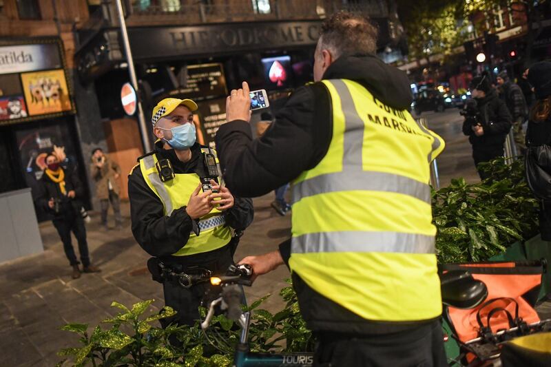 A Police officer is seen speaking with a man wearing a 'Covid Marshall' vest on November 5, 2020 in London, England. Getty Images