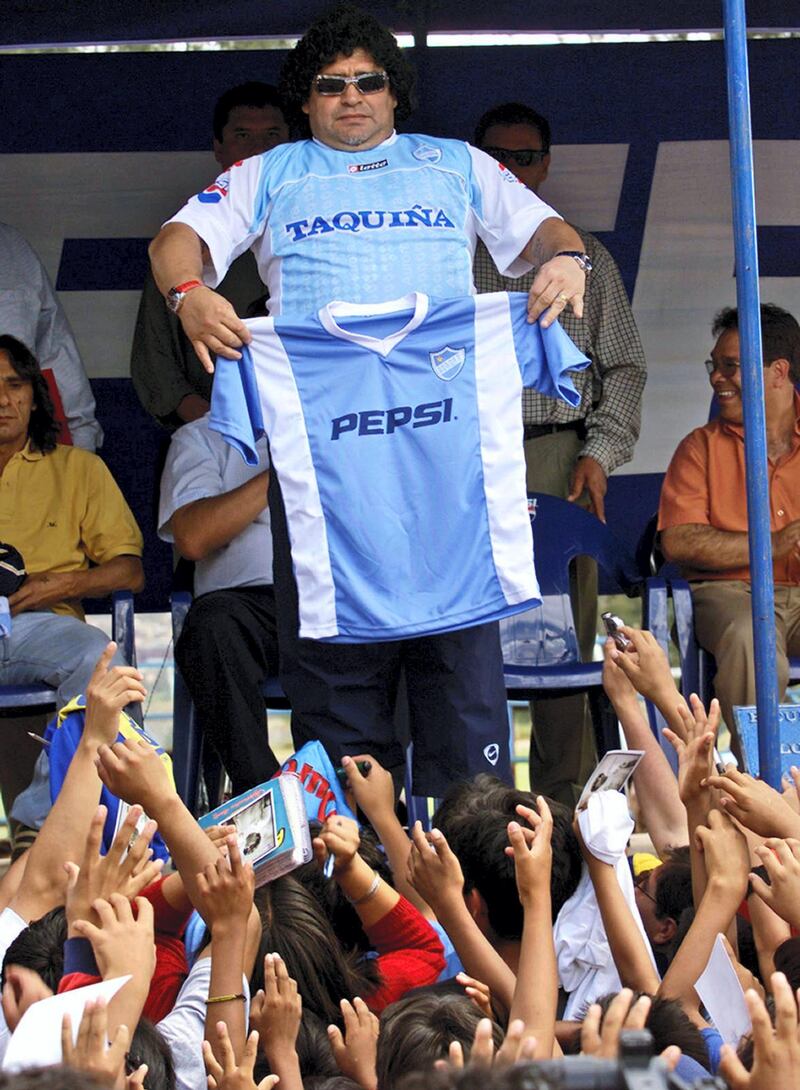 Argentine football legend Diego Armando Maradona shows a Aurora team shirt during the inauguration of the Club Aurora football School 06 March, 2004 in Cochabamba, Bolivia. Maradona was in charge of the school's opening.  AFP/PHOTO/Aizar RALDES (Photo by AIZAR RALDES / AFP)
