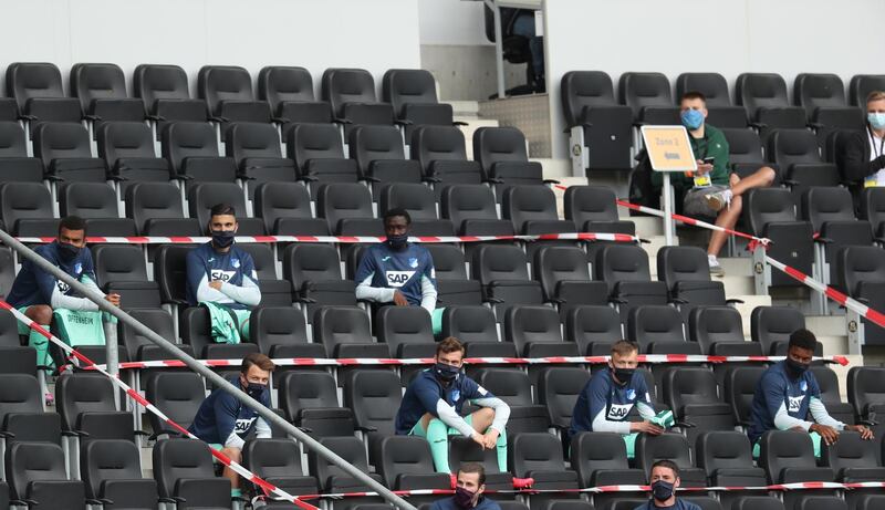 Substitute players of Hoffenheim wear protective masks and watch the match from the stands. EPA