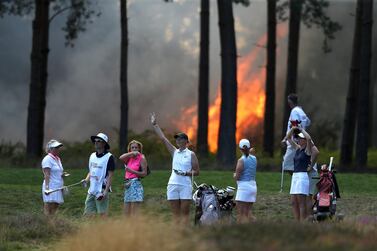 VIRGINIA WATER, ENGLAND - AUGUST 07: Players, Sophie Powell, Cara Gainer and Gabriella Cowley and their caddies look on as a fire nears the 10th hole during day three of The Rose Ladies Series on The West Course in the first ever ladies professional event at Wentworth Golf Club on August 07, 2020 in Virginia Water, England. (Photo by Naomi Baker/Getty Images)