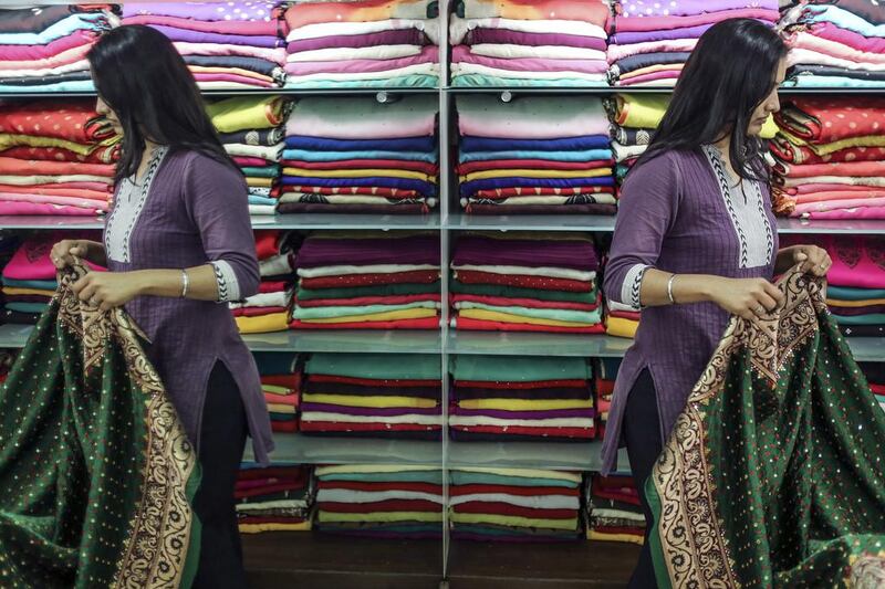 A customer is reflected in a mirror as she browses sarees in the Marine Lines area of Mumbai, India (Photographer: Dhiraj Singh/Bloomberg)