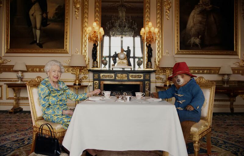 Britain's Queen Elizabeth II and Paddington Bear take cream tea at Buckingham Palace. PA