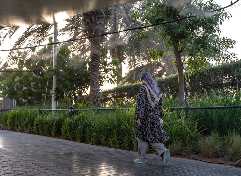 Abu Dhabu residents walk along the Corniche where a misting system is attached along the walkway to help beat the heat and humidity this summer on June 26th, 2021. Victor Besa / The National.