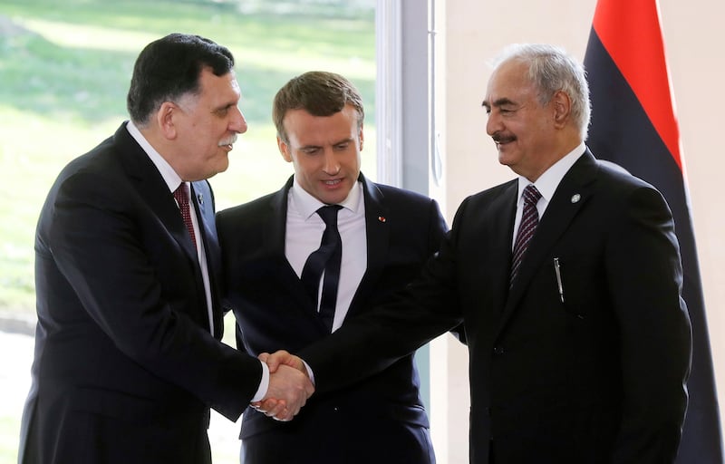 French president Emmanuel Macron looks on as Libyan prime minister Fayez Al Sarraj, left, shakes hands with Field Marshal Khalifa Haftar, commander in the Libyan National Army (LNA), after talks in La Celle-Saint-Cloud, near Paris, on July 25, 2017.Jacques Demarthon / AFP