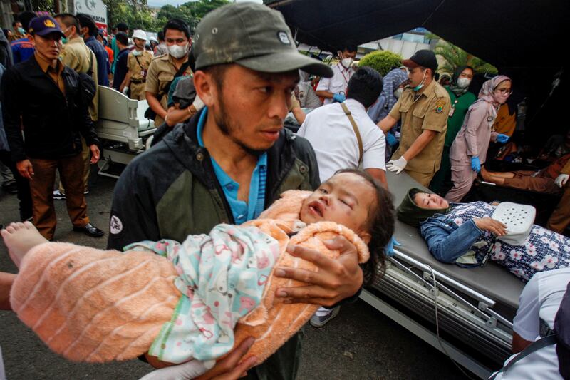 A man carries an injured child to a hospital in Cianjur. Reuters