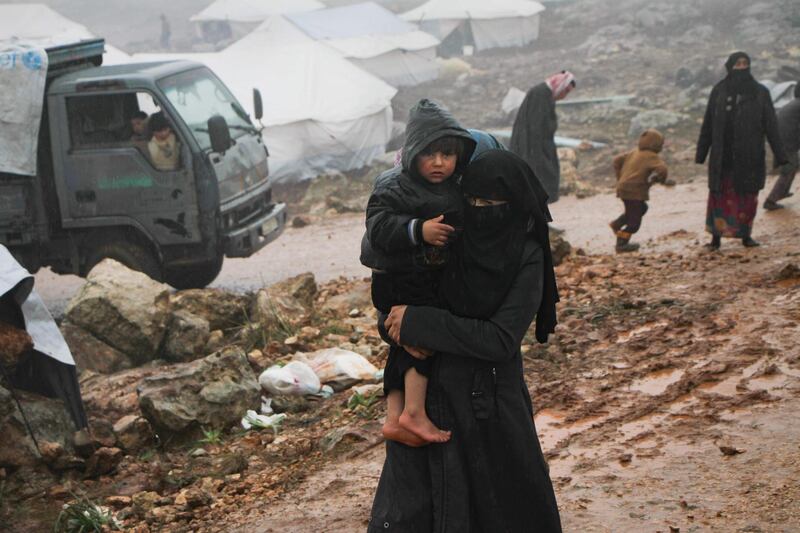 A Syrian woman who fled from government forces' advance on Maaret al-Numan in the south of the Idlib prvoince, carries a child at a camp for displaced people near the village of Harbnoush on December 27, 2019. Since mid-December, regime forces and their Russian allies have heightened bombardment on the southern edge of the final major opposition-held pocket of Syria, eight years into the country's devastating war. / AFP / Aref TAMMAWI
