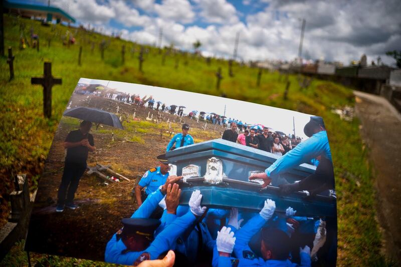 A printed photo taken on September 29, 2017 showing police lifting the coffin of officer Luis Angel Gonzalez Lorenzo, who was killed in the hurricane. The local police force of Aguadilla and Aguada is down by about a dozen officers since the storm, due to resignations and retirements.