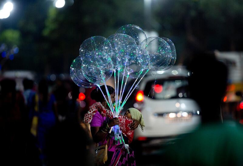 An Indian vendor carries an infant and stands on a street selling balloons in Hyderabad. Some 800 million people in the country live in poverty, many of them migrating to big cities in search of a livelihood and often ending up on the streets. AP