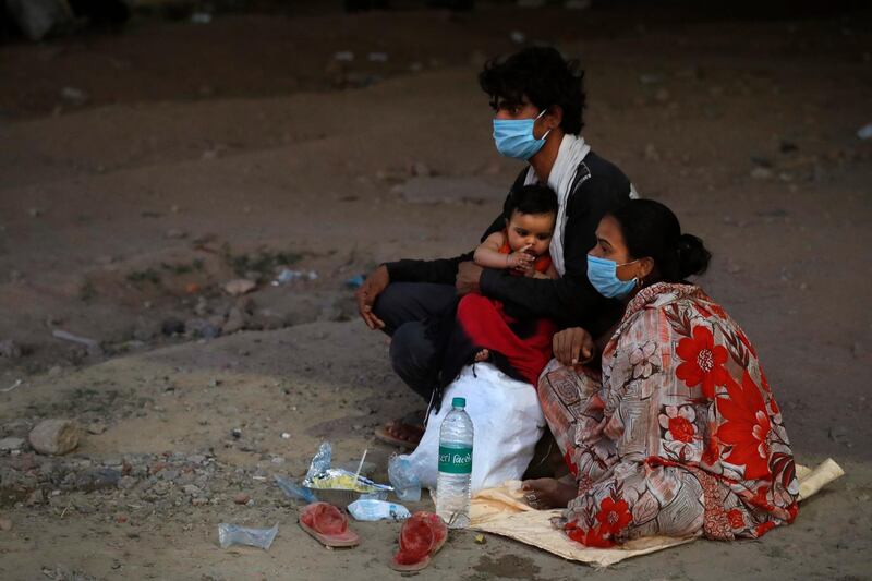 A migrant worker family with their three month old child wait under a flyover for transportation to get back to their village during a nationwide lockdown to curb the spread of new coronavirus in New Delhi, India. AP Photo