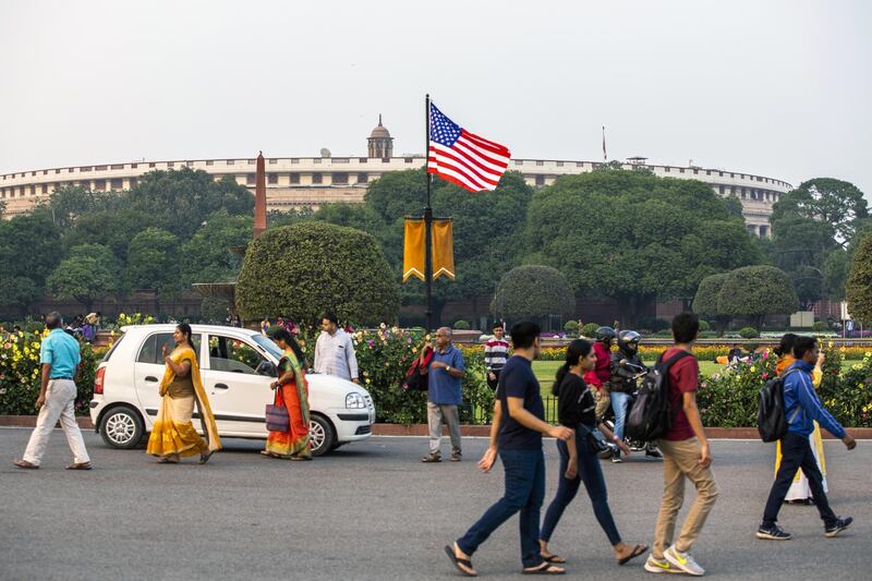 Pedestrians walk past an American flag flying from a post near Parliament House ahead of the arrival of US President Donald Trump in New Delhi, India. Bloomberg