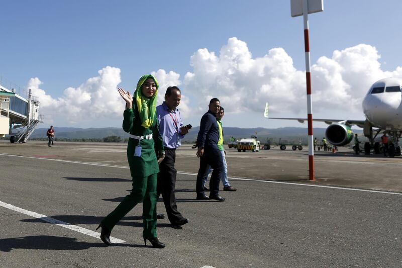 epa06487133 An airline stewardess wearing a hijab waves as she crosses the tarmac at Sultan Iskandar Muda Airport, Aceh, Indonesia, 31 January 2018. The government of Aceh issued new regulations for airline stewardesses, requiring them to wear a hijab as part of their uniform, in accordance with sharia law.  EPA/HOTLI SIMANJUNTAK