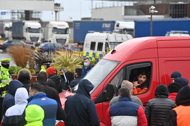 Drivers discuss by their vehicles in the road as they queue trying to enter the port of Dover in Kent, south east England, that is still cordoned after the UK and France agreed a protocol to reopen the border to accompanied freight arriving in France from the UK requiring all lorry drivers to show a negative Covid-19 test.  France and Britain reopened cross-border travel after a snap 48-hour ban to curb the spread of a new coronavirus variant threatened UK supply chains. Accompanied frieght will now be allowed to cross the channel from the port of Dover but all lorry drivers will require a lateral flow test and a negative Covid-19 result before the travel. AFP