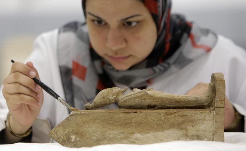 An Egyptian conservator works on an ancient Pharaonic wooden statue of the Egyptian god Osiris, at the wood laboratory of the restoration center of the partially opened complex of the Grand Egyptian Museum in Cairo. Amr Nabil / AP Photo