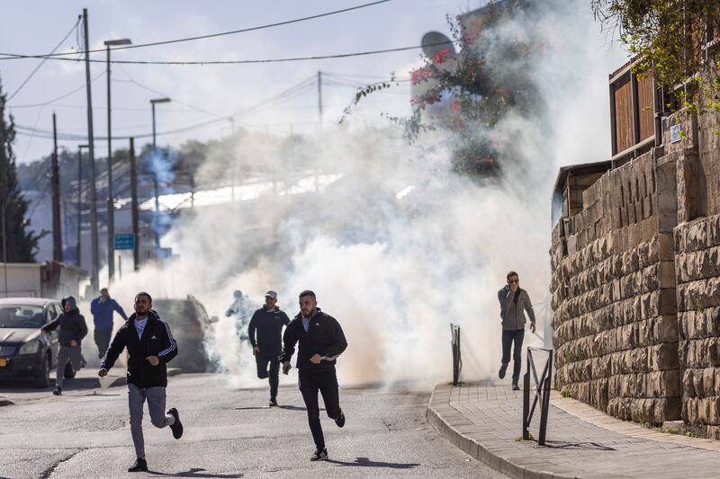 Palestinians run from tear gas fired by Israeli border police during Friday prayers along a road outside the Old City of Jerusalem. Getty Images