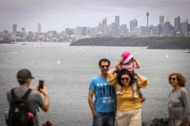 People pose for photographs in front of yachts and ferries as they sail on Sydney Harbour during Boxing Day this year. Human contact has been a challenge for most people in a year ravaged by coronavirus pandemic. Getty Images