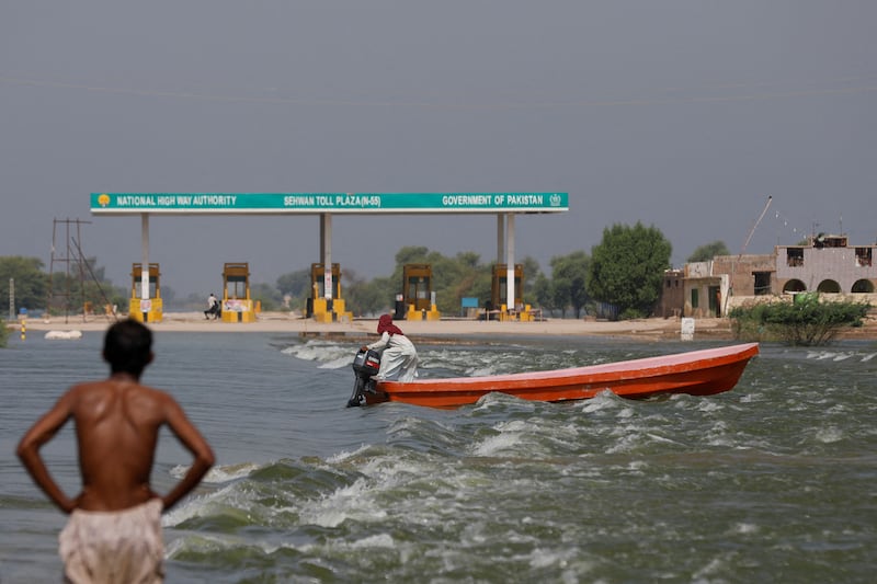 A boat passes a toll plaza on a flooded motorway in Sehwan, Pakistan, on September 15. Reuters