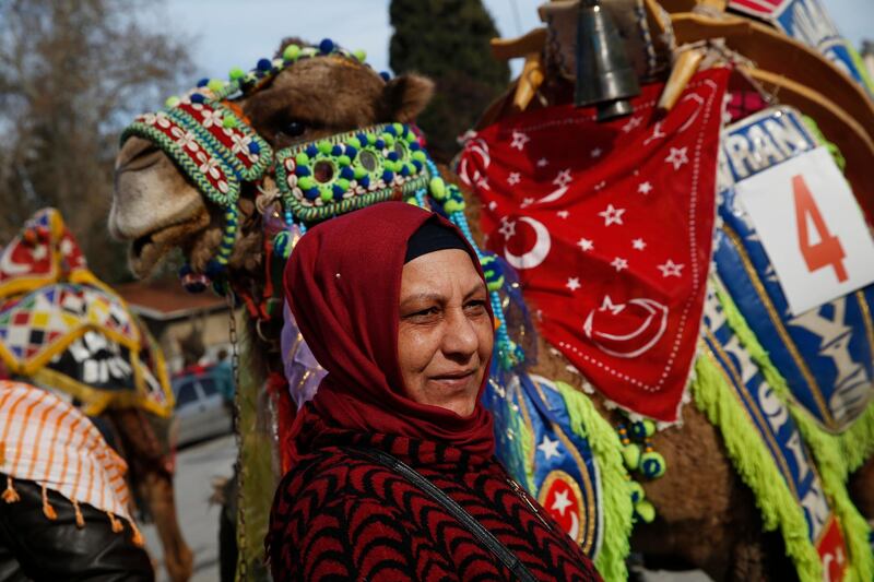 A woman poses for a picture in front of a camel. AP
