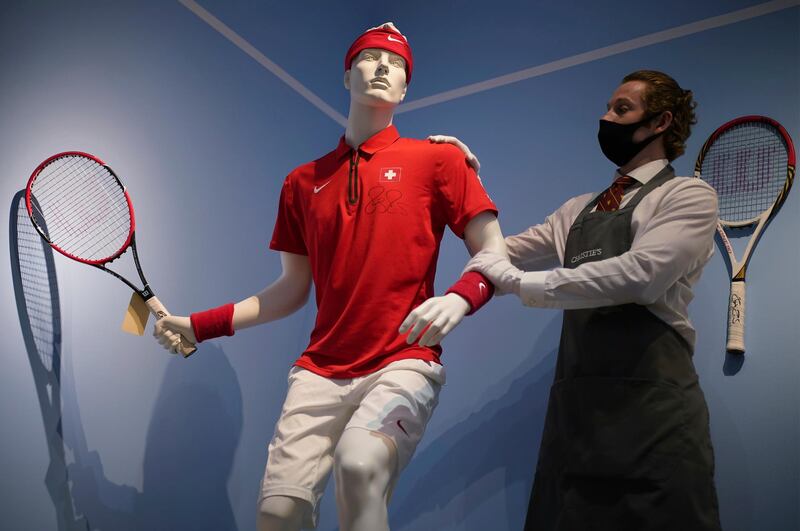 A Christie's technician poses next to a model wearing Swiss tennis player Roger Federer's kit and racket used in the Davis Cup, 2014 on display, at Christie's in London.