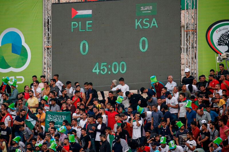 Football fans stand at half-time beneath a display showing the score. AFP