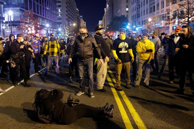 A woman lies on the ground surrounded by members of far-right militia Proud Boys during a scuffle following a protest against election results, in Washington, US. Reuters