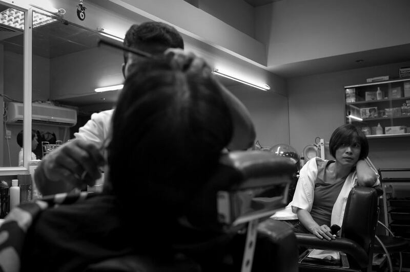 A man gets a haircut at a saloon (barber shop) in the Al Zahiyah area of Abu Dhabi while another barber looks on. Brian Kerrigan / The National