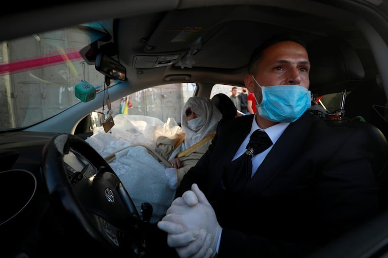 A Palestinian groom, Rafeh Qassim, wears a mask as he sits in a car with his bride on their wedding day, in Ramallah in the Israeli-occupied West Bank. Reuters