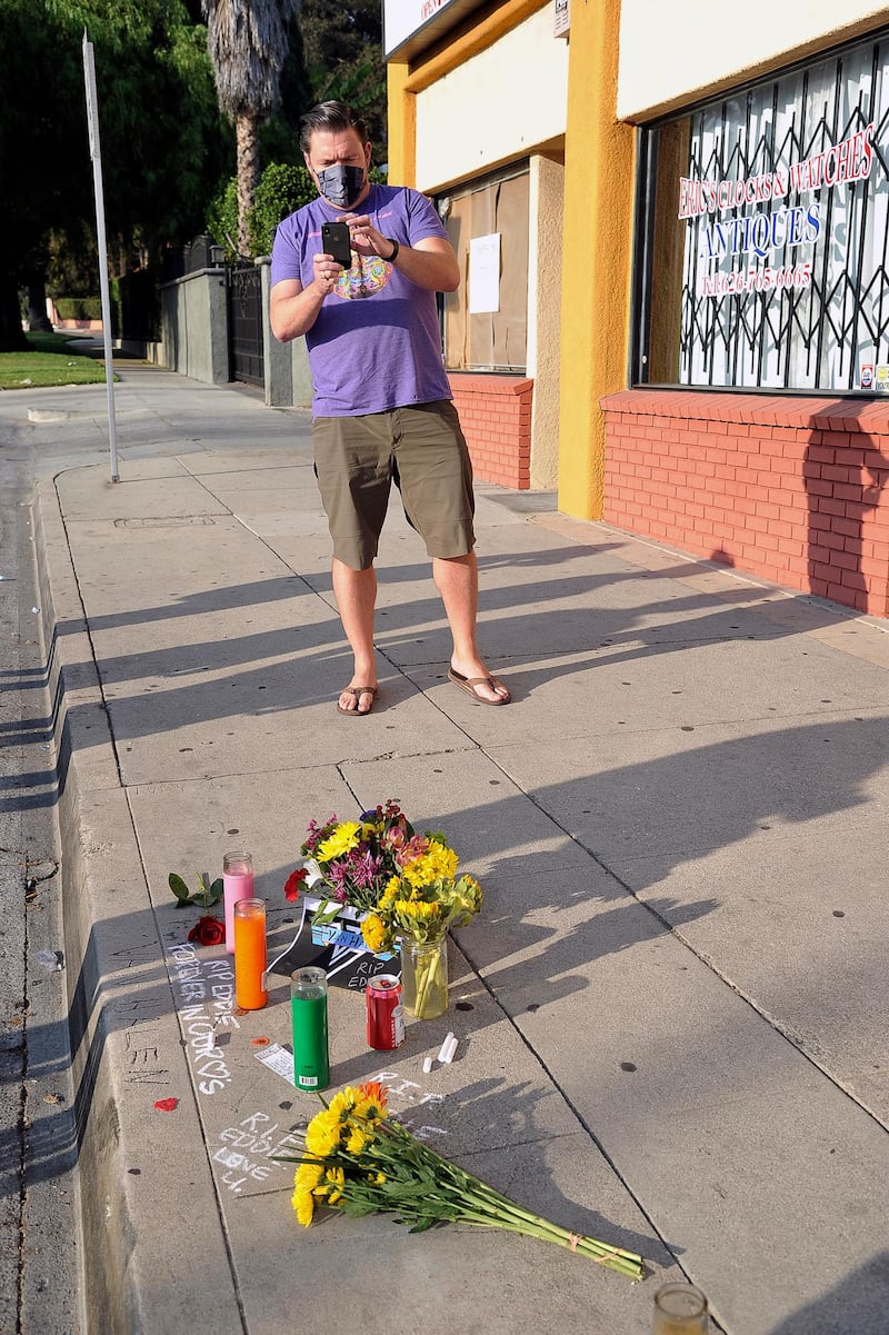 An Eddie Van Halen fan photographs a makeshift memorial for the late musician near Van Halen's childhood home in Pasadena, California. AP
