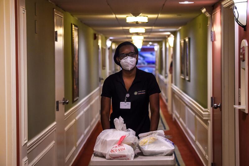 Shanika Williams wears a facemask as she delivers food in John Knox Village, a retirement community in Pompano Beach some 40 miles north of Miami, Florida on August 7, 2020. About 900 retirees live in the John Knox Village senior community in Pompano Beach, South Florida. Of these, about 400 have learned to use technology to order food to their apartments, communicate with each other or participate in online social activities. Thirty of them participate in a book club over Zoom since the pandemic began. Florida, a coronavirus hotspot with nearly 8,000 deaths, is the US state with the highest proportion of elderly people, which is also the population most vulnerable to the disease. 20% of its 21 million inhabitants are over 65, according to a 2019 Population Reference Bureau study. / AFP / CHANDAN KHANNA
